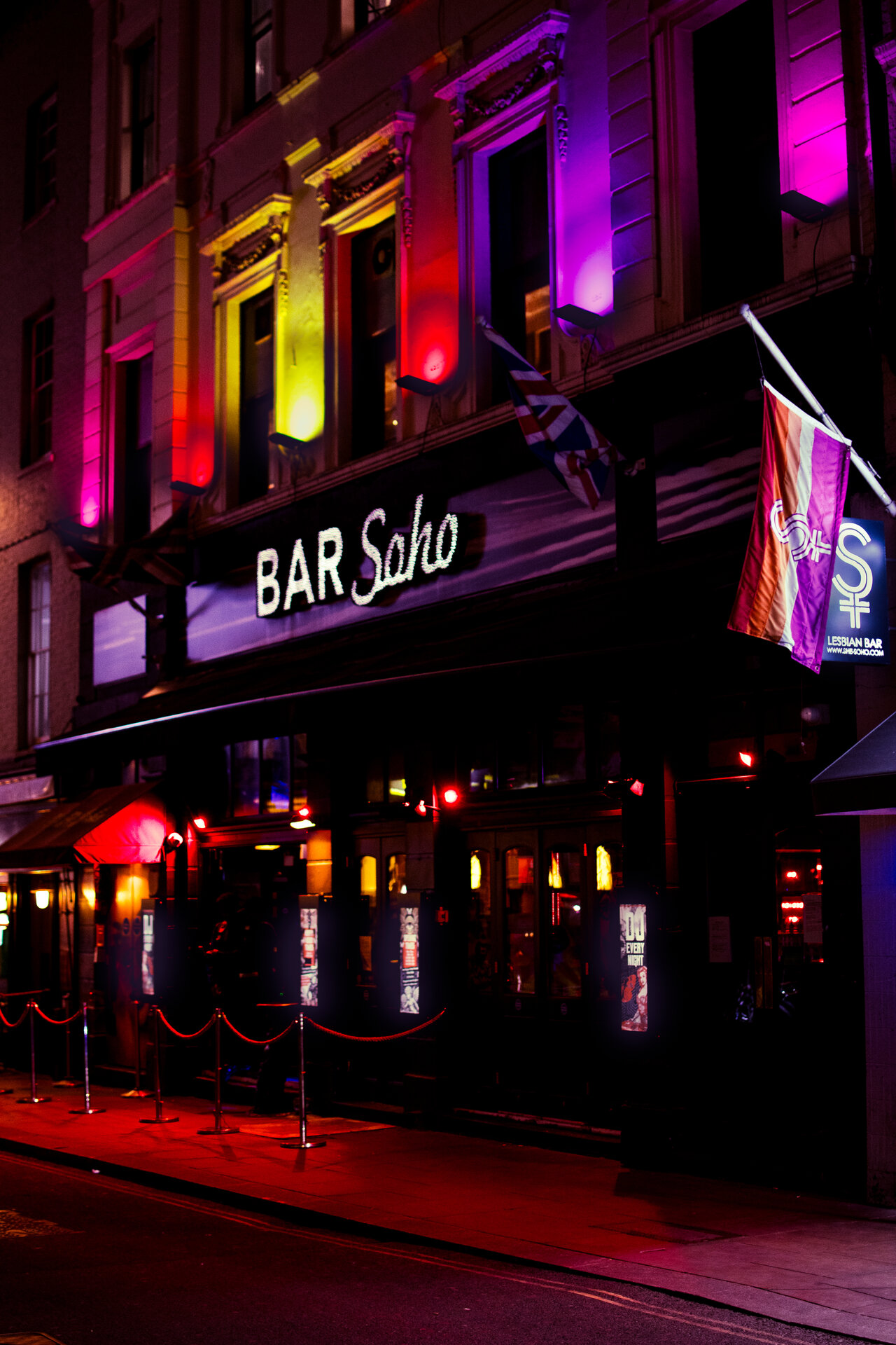 Bar Soho facade with vivid pink and green neon signage at night