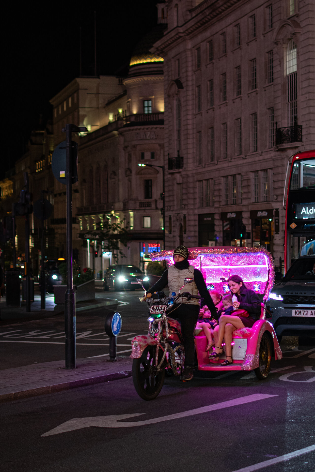 Illuminated pedicab at Piccadilly Circus surrounded by neon and crowds
