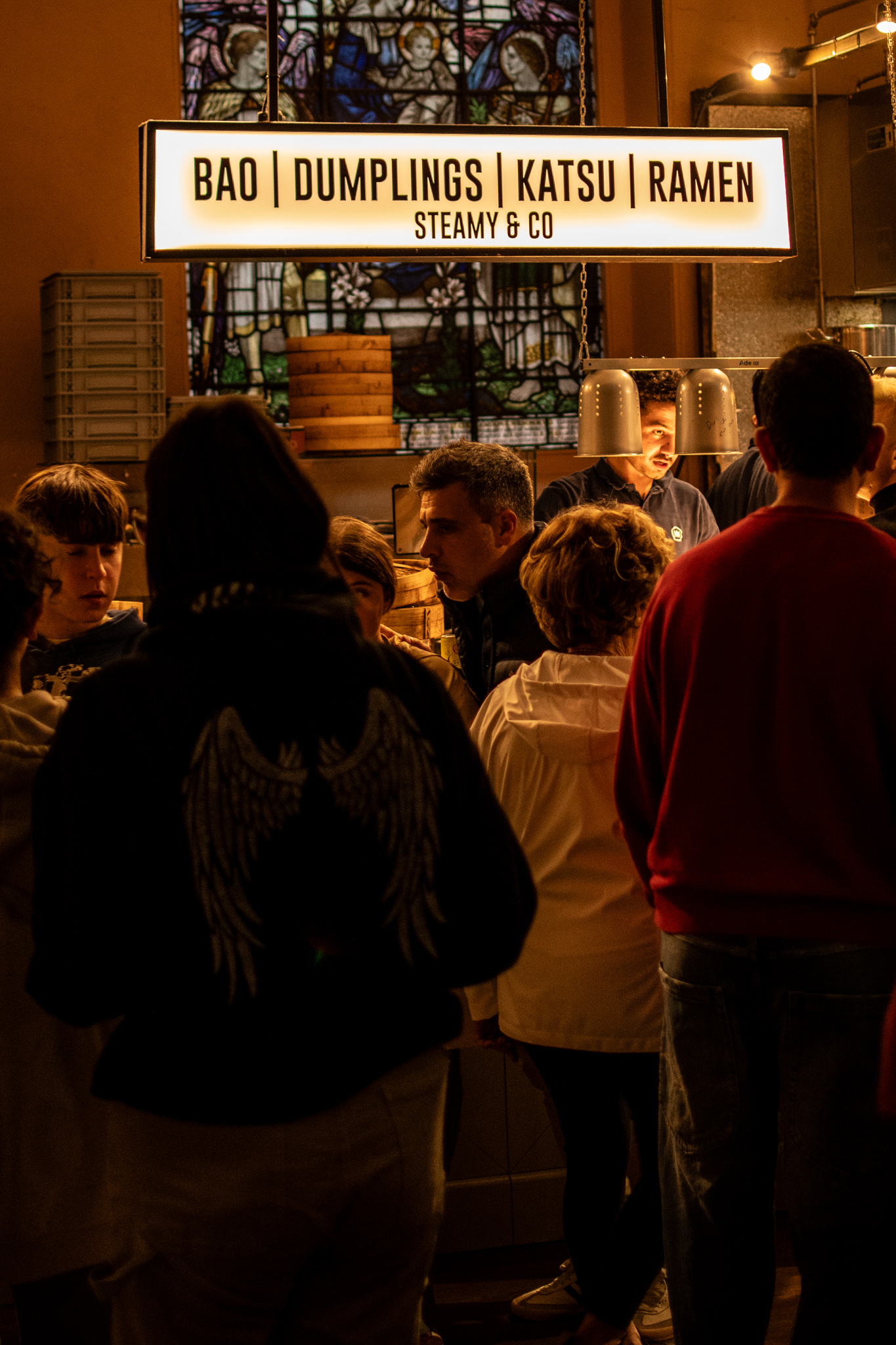 Upscale food hall inside a deconsecrated church, warm light and crowds at night