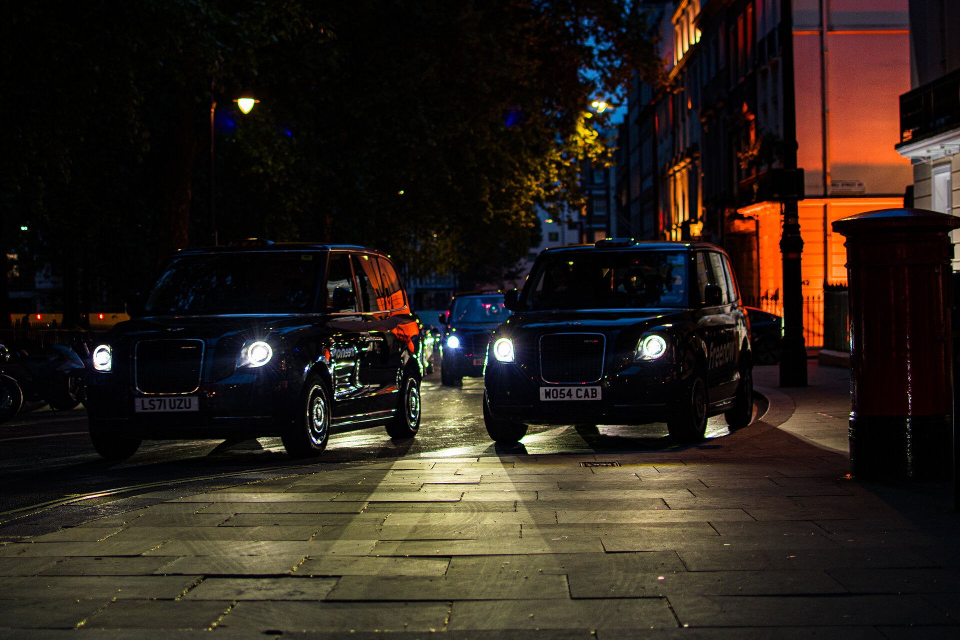 London black cab headlights coming toward camera on a quiet night street