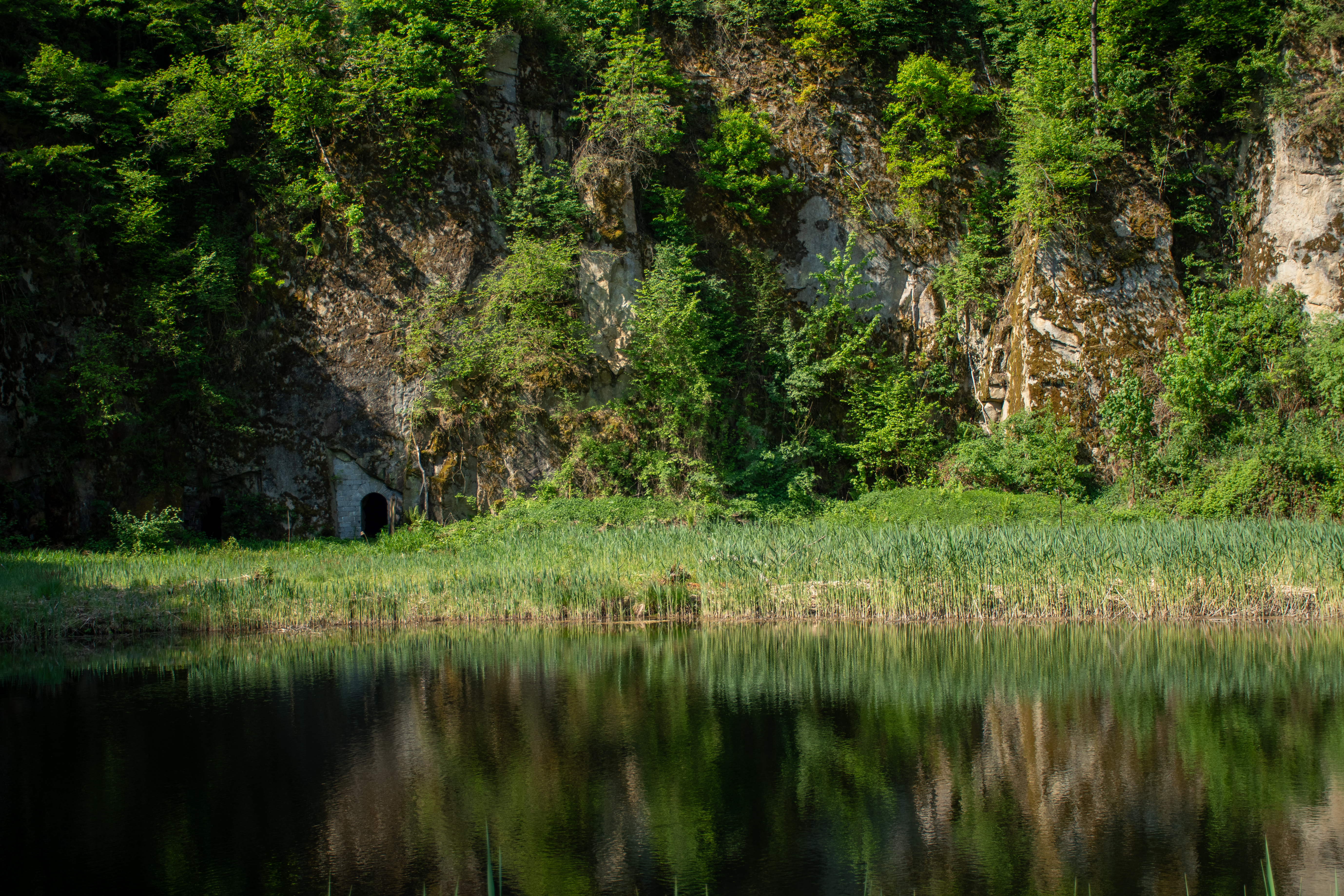The quarry floor with a still pond reflecting the rock walls and sky