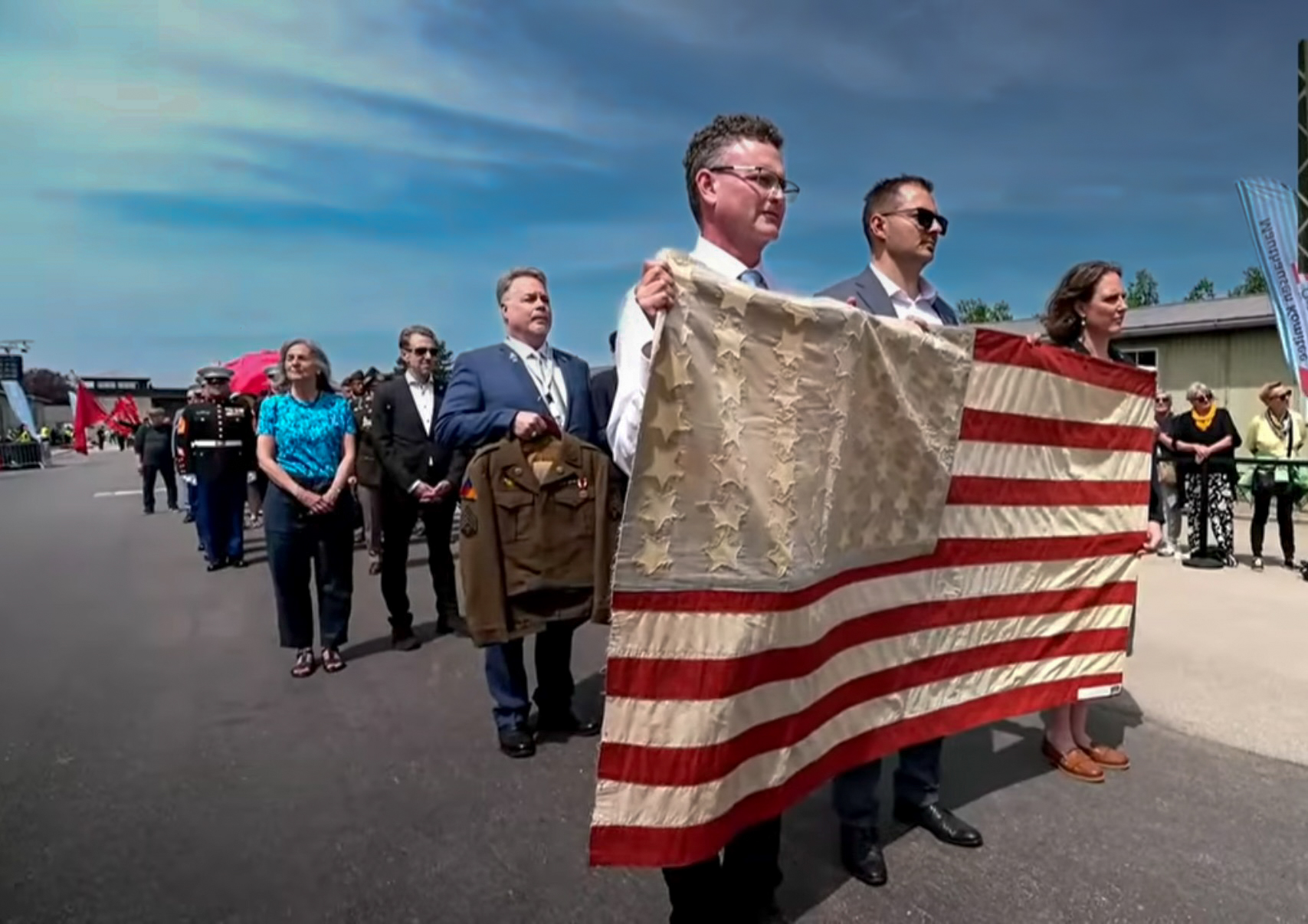 Rob Pettit carrying the prisoners' handmade American flag with 56 stars through Mauthausen