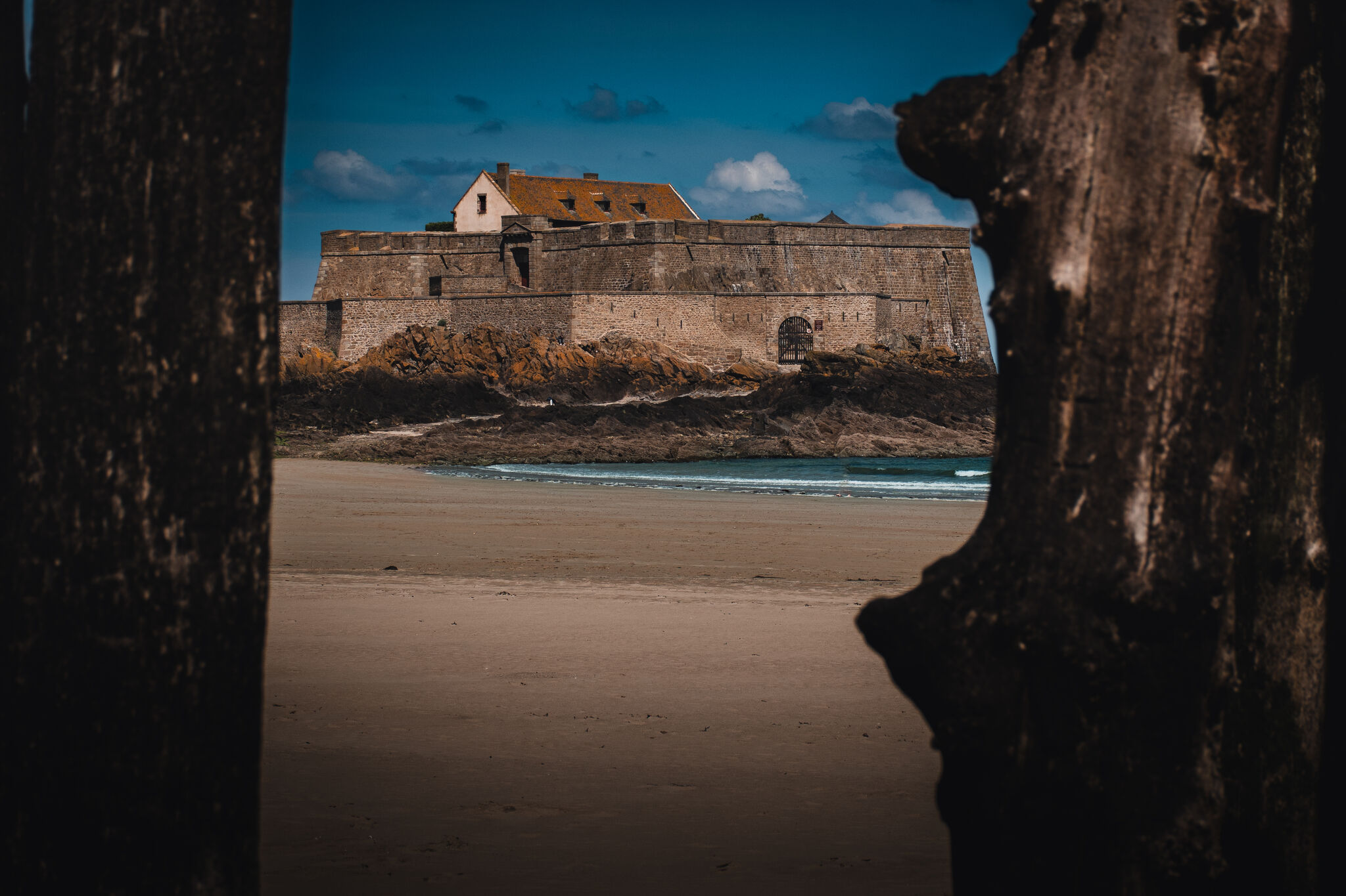 Fort National seen through weathered wooden posts on the beach