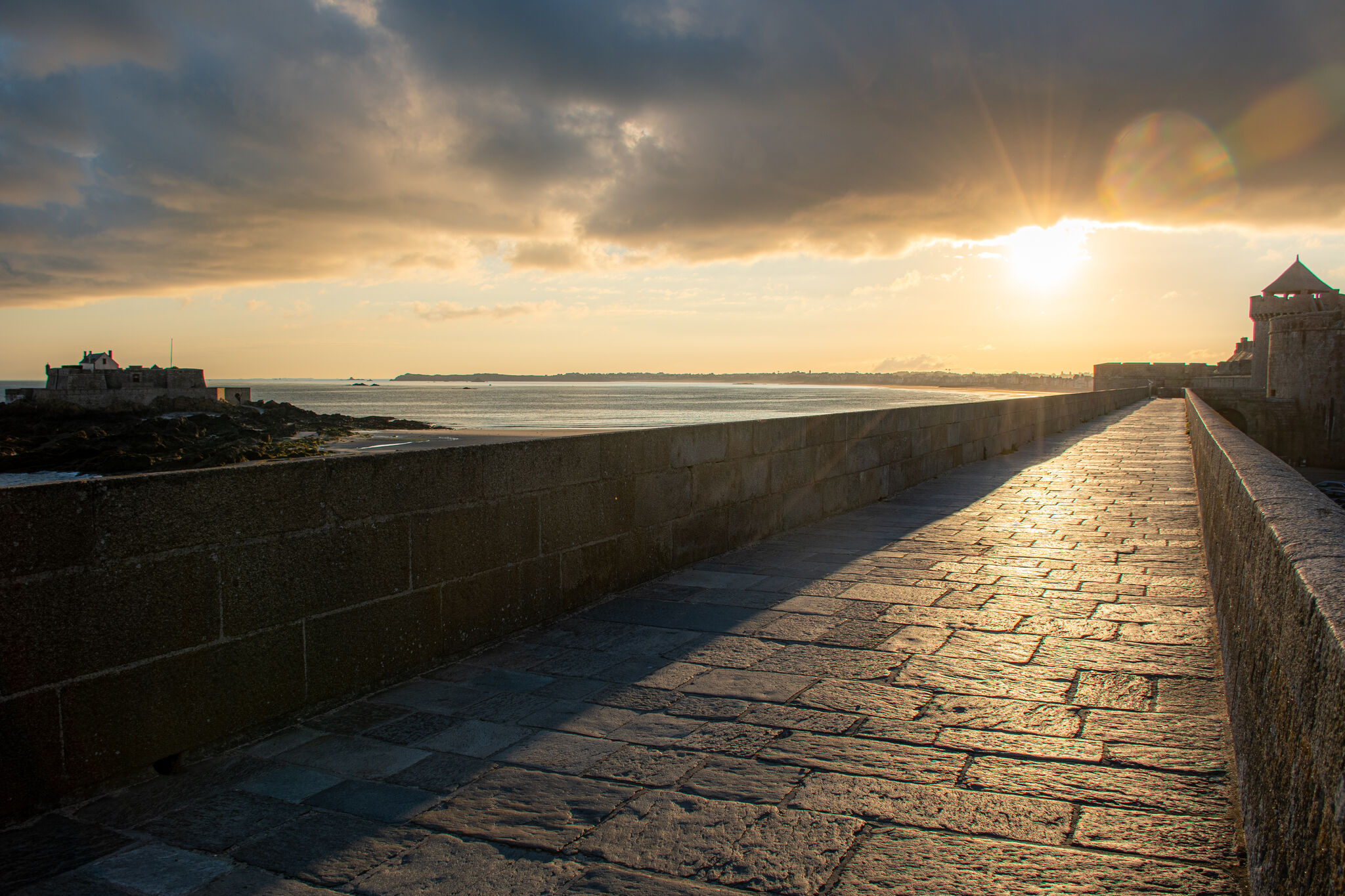 Rampart walkway heading southeast into the rising sun, Fort National to the left at sunrise