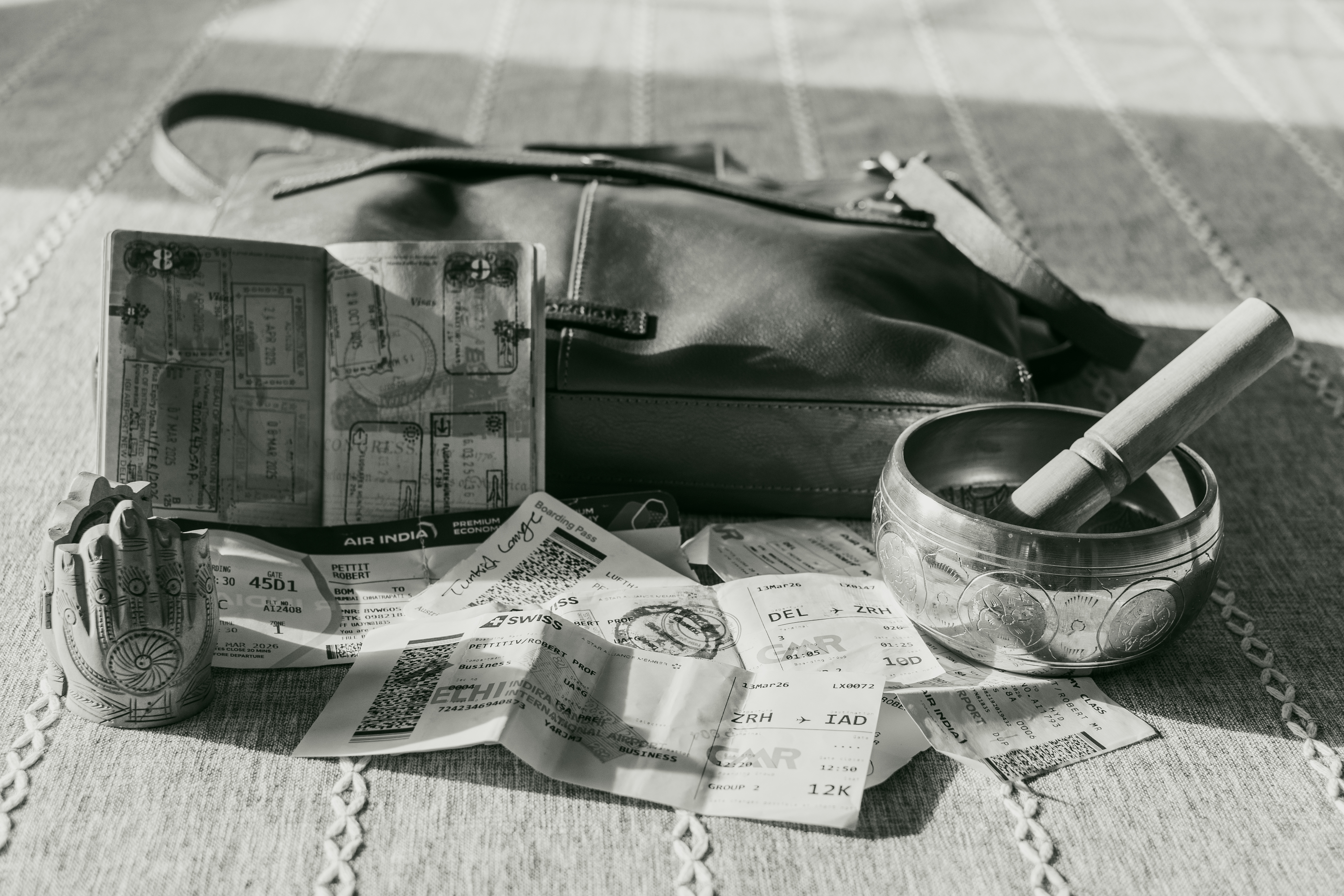 Passport, boarding passes, singing bowl and Hamsa figurine on a table